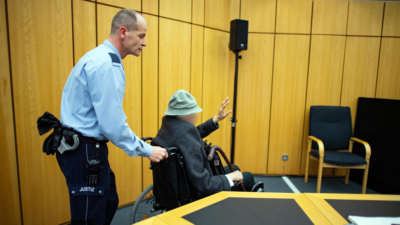 Zu Beginn des Prozesses schiebt ein Justizbeamter den Angeklagten mit dem Rollstuhl in den Sitzungssaal.