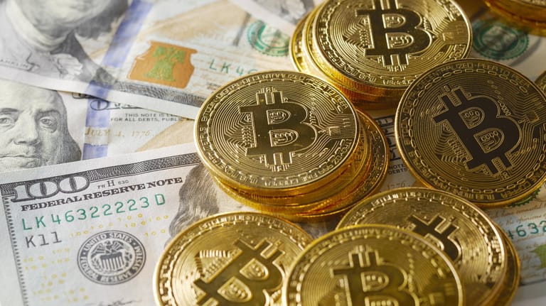 Symbolische Bitcoin-Münzen liegen auf Geldscheinen: Um Bitcoins zu schürfen, werden immer aufwändigere Rechenprozesse nötig – und das verbraucht Energie. (Symbolbild)