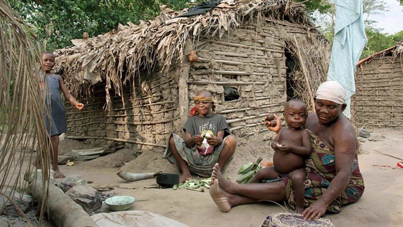 Eine Pygmäen-Frau vom Volk der Basua bereitet im Westen von Uganda vor einer Hütte Essen zu.