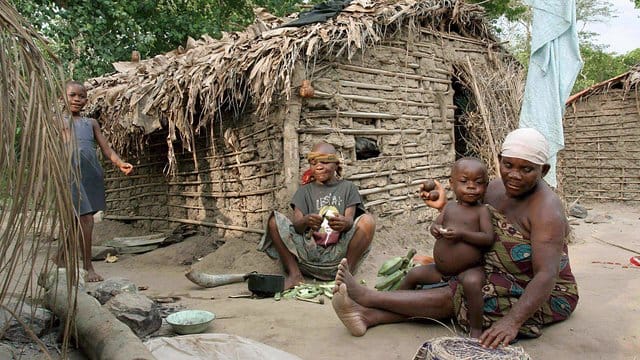 Eine Pygmäen-Frau vom Volk der Basua bereitet im Westen von Uganda vor einer Hütte Essen zu. Eine Pygmäen-Frau vom Volk der Basua bereitet im Westen von Uganda vor einer Hütte Essen zu.
