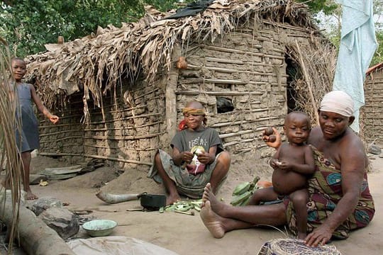 Eine Pygmäen-Frau vom Volk der Basua bereitet im Westen von Uganda vor einer Hütte Essen zu.
