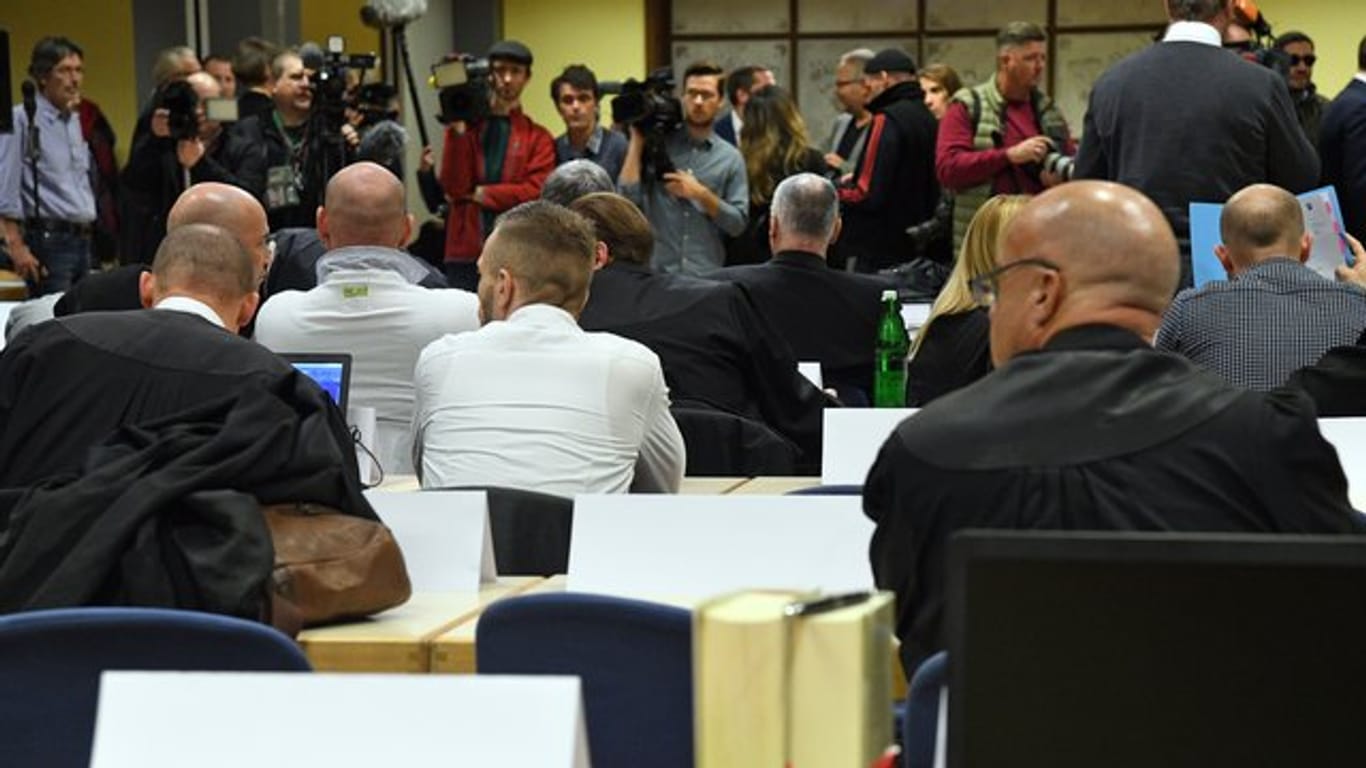 Die Angeklagten und ihre Anwälte sitzen vor Beginn ihres Prozesses in einem Saal in der Siegerlandhalle.