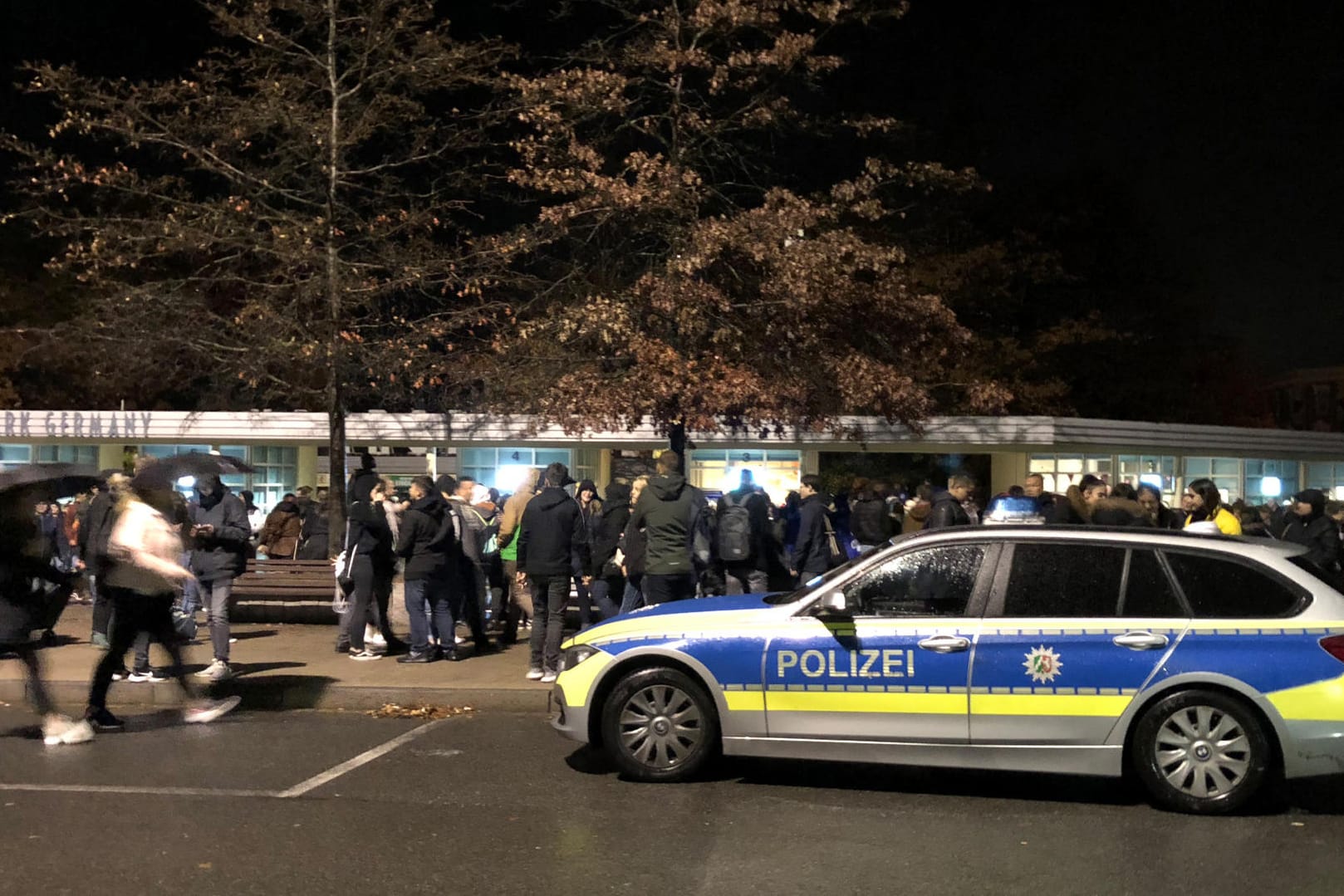 Ein Polizeiwagen und zahlreiche Menschen stehen vor dem Eingang des Movie Parks Germany: Nach einer Bombendrohung hat die Polizei den Freizeitpark geräumt.