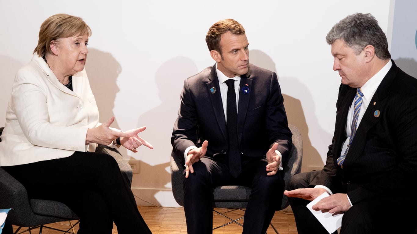 Angela Merkel, Emmanuel Macron und Petro Poroschenko sitzen beim Paris Friedens Forum für ein Gespräch zusammen: Die Regierungschefs haben die Wahlen in der Ostukraine als rechtswidrig verurteilt.