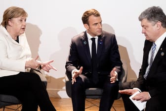 Angela Merkel, Emmanuel Macron und Petro Poroschenko sitzen beim Paris Friedens Forum für ein Gespräch zusammen: Die Regierungschefs haben die Wahlen in der Ostukraine als rechtswidrig verurteilt.