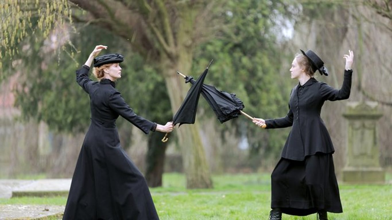 Esther Schweins (l) in der Rolle von Emmeline Pankhurst und Anke Retzlaff als ihre Tochter Christabel kämpfen mit Regenschirmen.