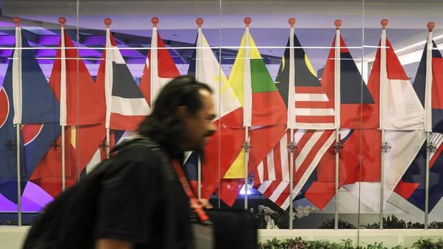 Ein Journalist passiert in Singapur die Flaggen von teilnehmenden Ländern des Asean-Gipfels. Ein Journalist passiert in Singapur die Flaggen von teilnehmenden Ländern des Asean-Gipfels.