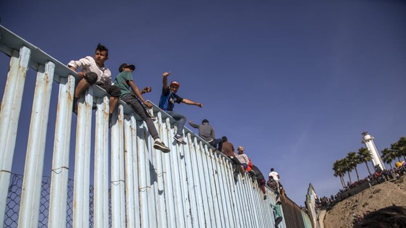 Migranten aus Mittelamerika sitzen in Tijuana auf dem Grenzzaun zwischen Mexiko und den USA.