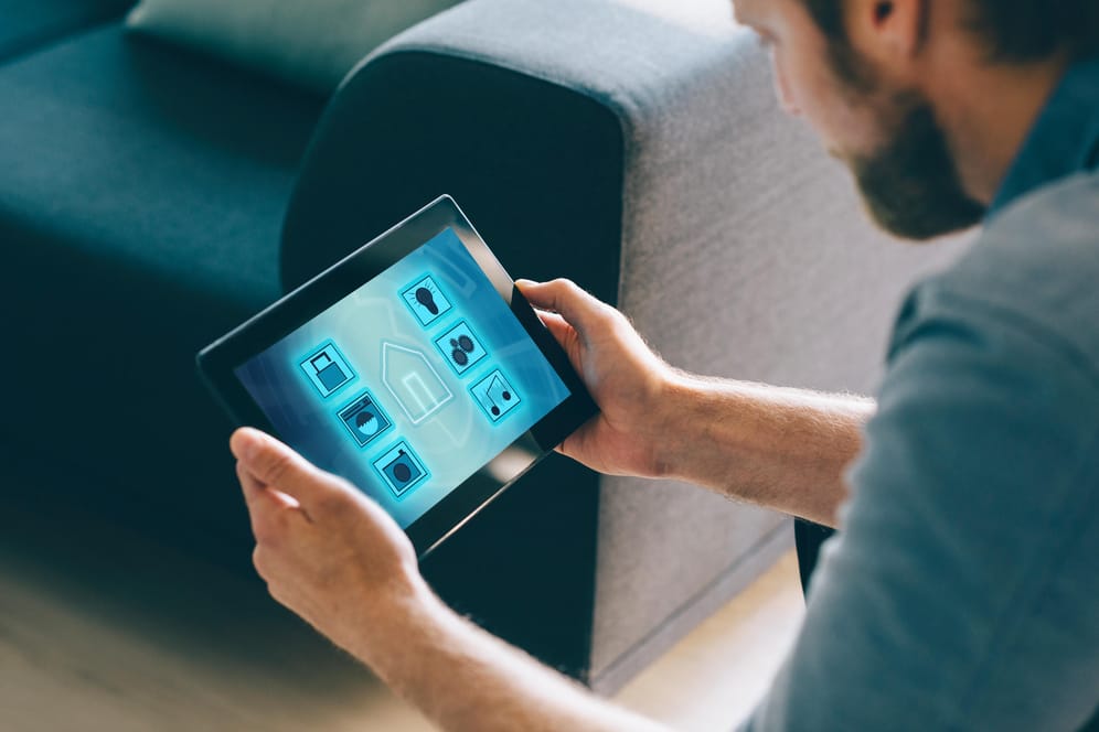 Ein Mann nutzt ein Tablet mit Smart-Home-Apps: Viele smarte Geräte haben Sicherheitslücken.