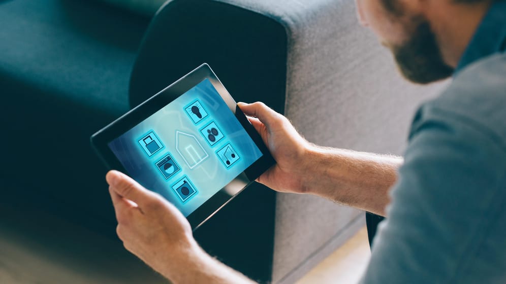Ein Mann nutzt ein Tablet mit Smart-Home-Apps: Viele smarte Geräte haben Sicherheitslücken.