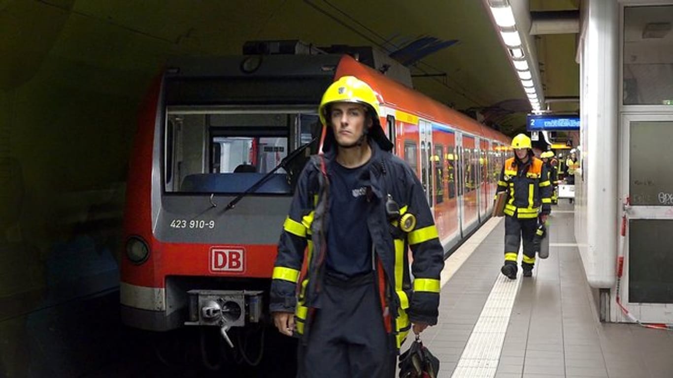 Feuerwehrleute gehen an einer S-Bahn in der Frankfurter Bahnstation Ostendstraße vorbei, wo es zu dem tödlichen Unfall kam.