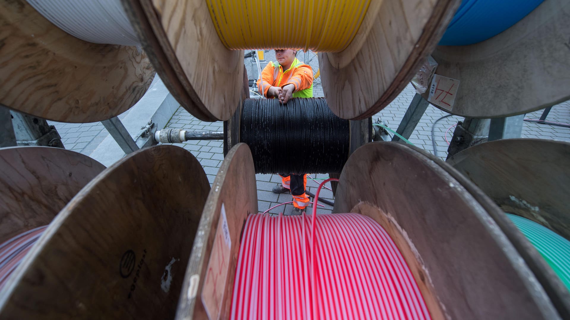 Eine Fachkraft für Lichtwellenleiterinstallation zieht Glasfaserkabel von einer Kabeltrommel gezogen wird: Der Breitbandausbau in Deutschland steht seit Jahren in der Kritik.