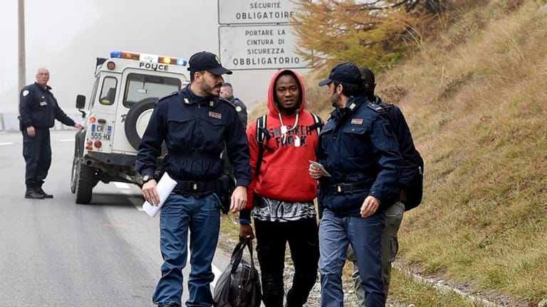 Italienische Polizisten überprüfen einen Mann nahe der Grenze zu Frankreich.
