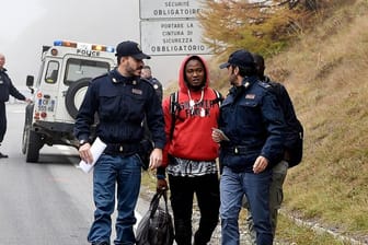 Italienische Polizisten überprüfen einen Mann nahe der Grenze zu Frankreich.