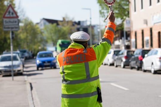 Ein Polizist hält im Rahmen einer Geschwindigkeitsmessung einen Autofahrer an.