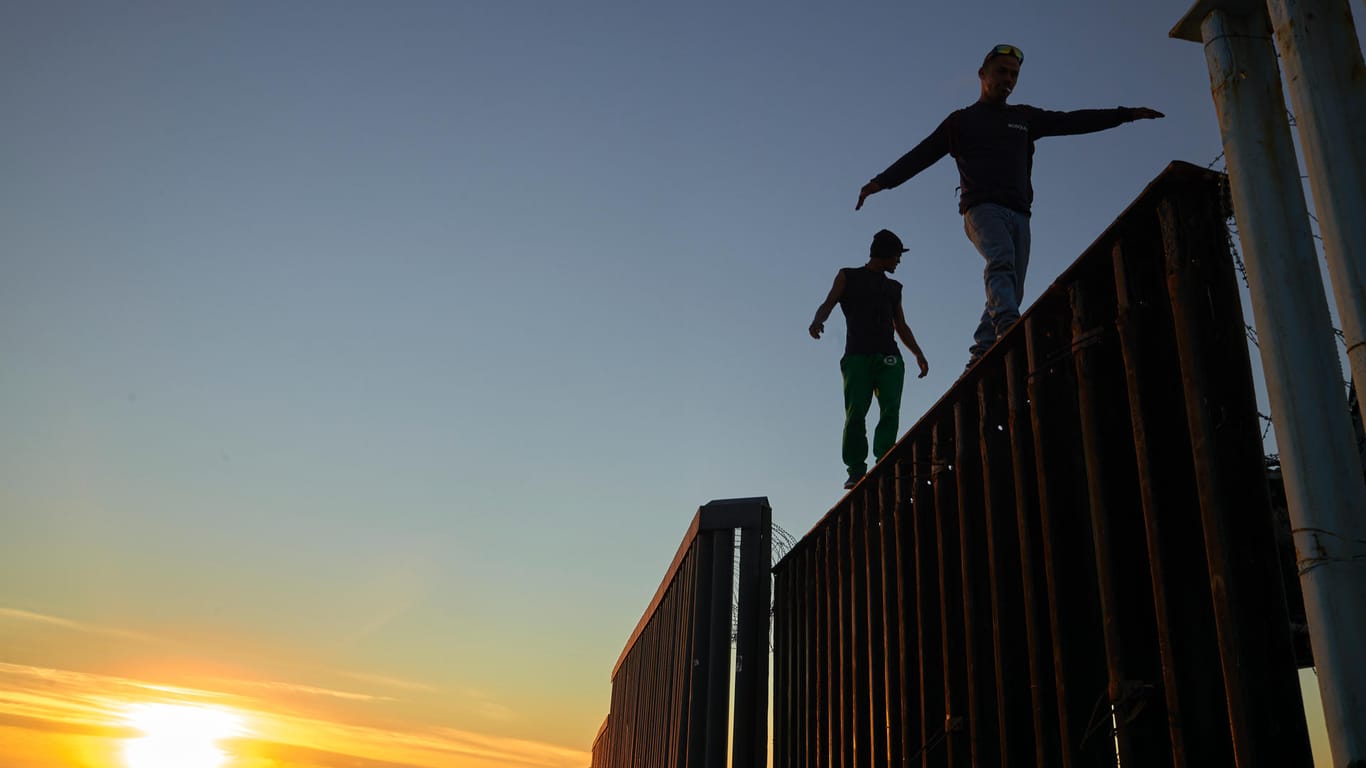 Zwei Migranten balancieren auf dem Grenzzaun zwischen Mexiko und den USA: Die ersten Asylsuchende aus der Migranten-Karawane sind schon da, Freitag werden weitere Tausende erwartet.