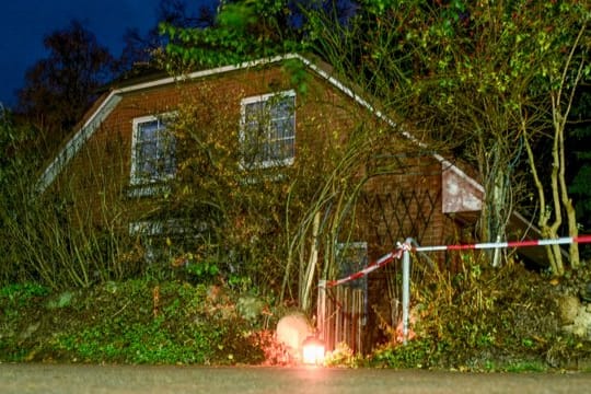 Eine Grableuchte steht neben einer Polizeiabsperrung am Eingang zu einem Haus in Wittenburg.