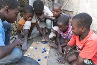 Kinder einer Siedlung in Mosambik spielen ein Brettspiel mit Plastikflaschenverschlüssen: Von den 15 Ländern mit der höchsten gesellschaftlichen Verwundbarkeit liegen 13 in Afrika.
