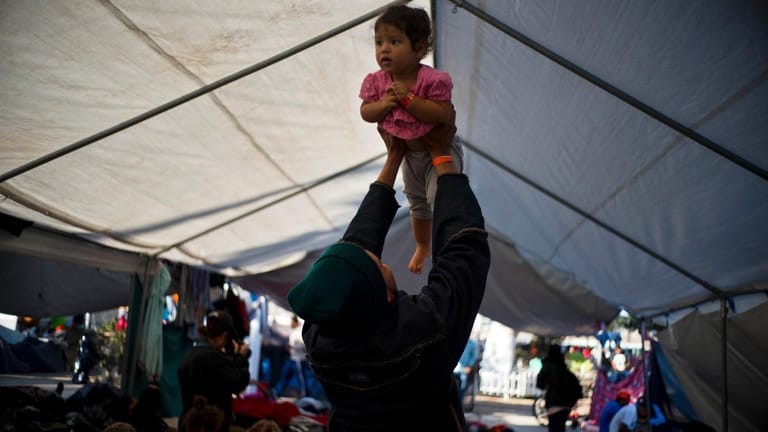Ein Migrant aus Honduras spielt mit seiner Tochter: Während viele in Tijuana den Migranten gegenüber positiv eingestellt sind, haben einige Anwohner die Einwanderer ausgebuht, mit Steinen beworfen und auch geschlagen.