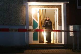 Polizeibeamte stehen im Eingang eines Wohnhauses in Jena: Hier wurden vier Leichen gefunden.