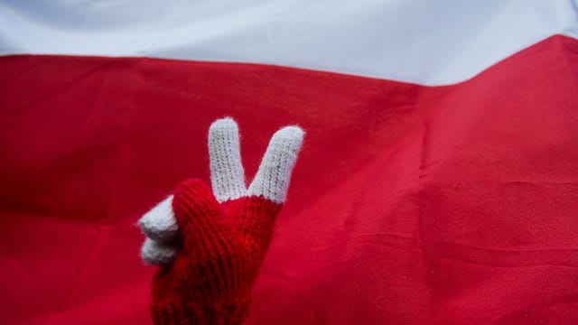 Peace-Zeichen vor polnischer Nationalflagge während eines Protests gegen die Justizreform. Peace-Zeichen vor polnischer Nationalflagge während eines Protests gegen die Justizreform.