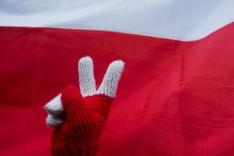Peace-Zeichen vor polnischer Nationalflagge während eines Protests gegen die Justizreform.
