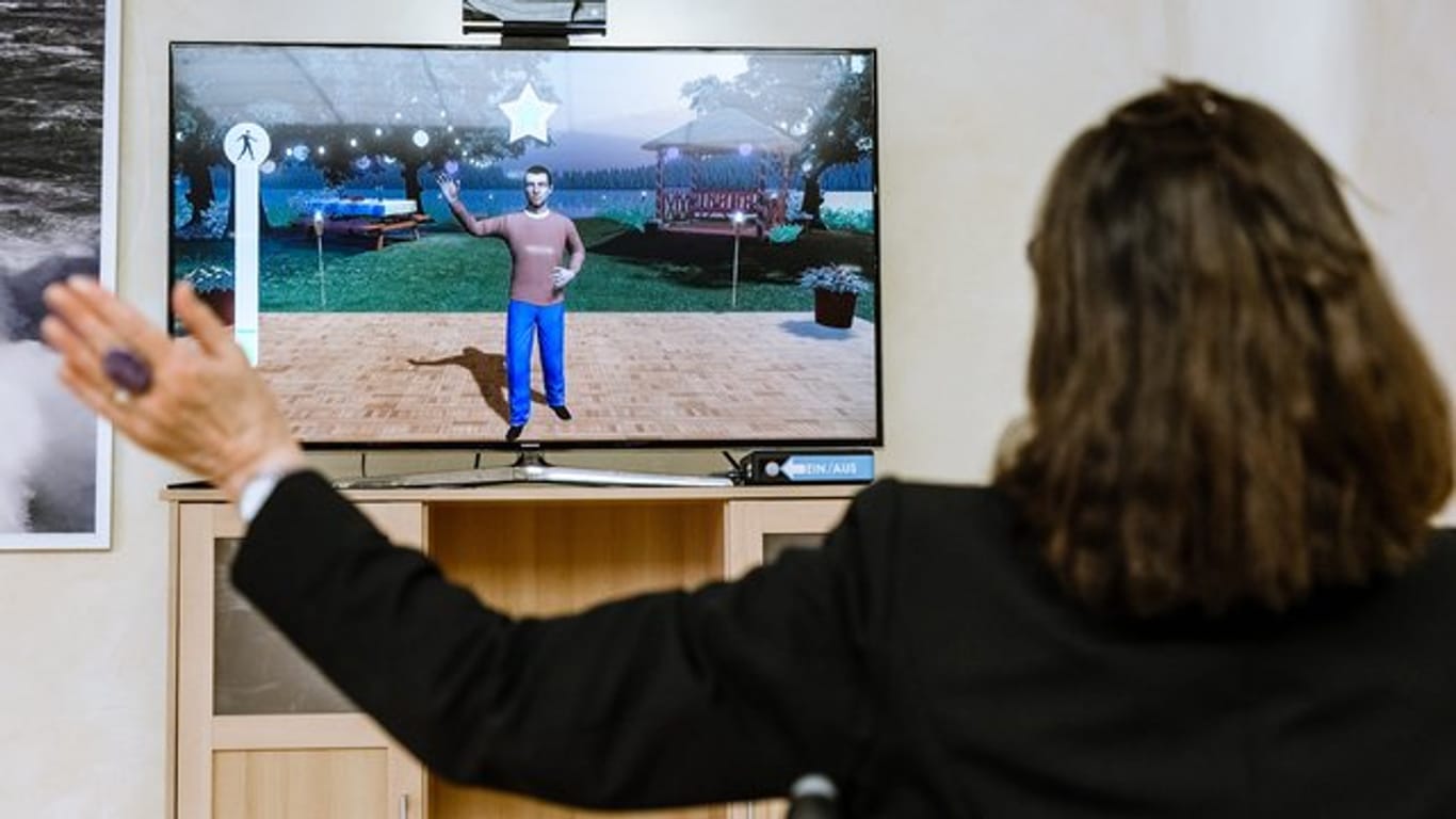 Eine Pflegeheimbewohnerin steuert in einem therapeutischen Videospiel aus dem Rollstuhl heraus ihren Avatar durch Armbewegungen.