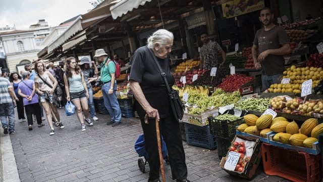 Eine ältere Frau geht in Athen an Marktständen vorbei. Eine ältere Frau geht in Athen an Marktständen vorbei.
