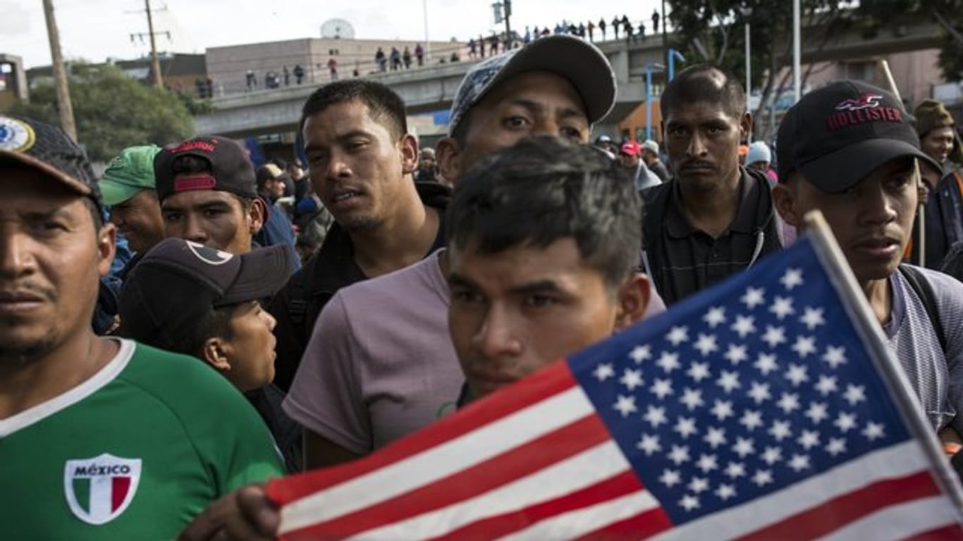 Ein Migrant mit der US-Flagge am Grenzübergang Mexiko-USA im mexikanischen Tijuana.
