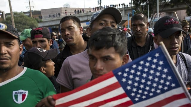 Ein Migrant mit der US-Flagge am Grenzübergang Mexiko-USA im mexikanischen Tijuana. Ein Migrant mit der US-Flagge am Grenzübergang Mexiko-USA im mexikanischen Tijuana.