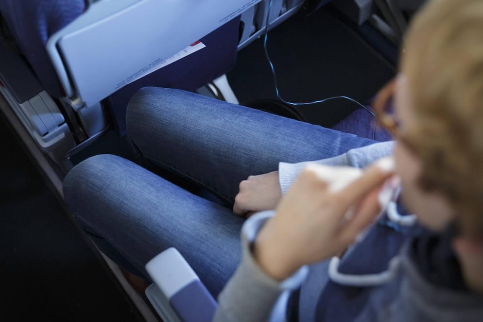 Flugpassagier sitzt schräg im Sitz: Nicht nur für übergewichtige Personen ist fliegen oft wenig komfortabel.