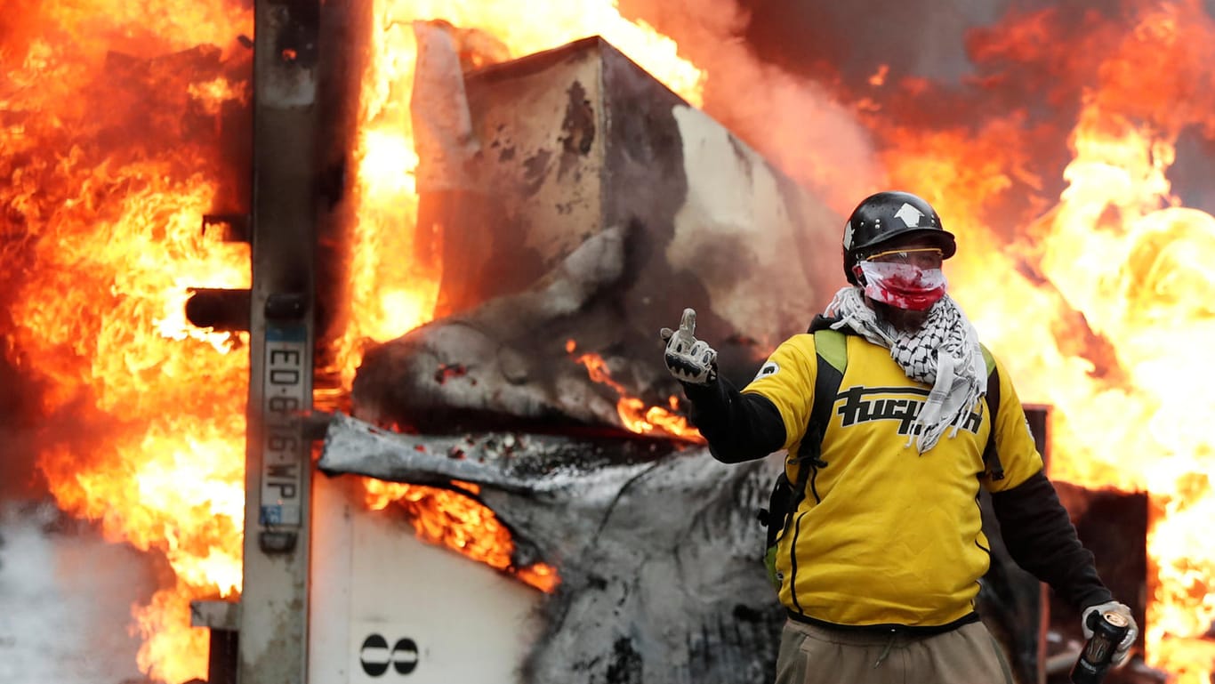 Ein vermummter Demonstrant vor einem brennenden Fahrzeug auf den Champs-Elysées in Paris: Die Kundgebung der "Gelbwesten" führte zu schweren Ausschreitungen.