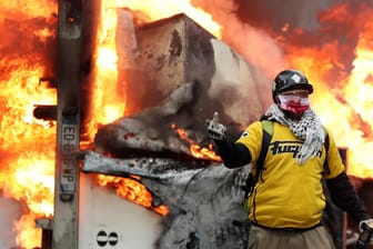 Ein vermummter Demonstrant vor einem brennenden Fahrzeug auf den Champs-Elysées in Paris: Die Kundgebung der "Gelbwesten" führte zu schweren Ausschreitungen.