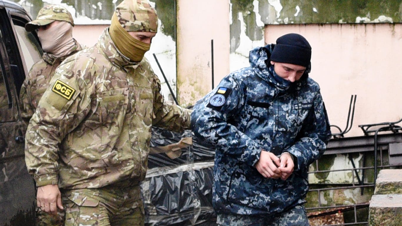 Ein ukrainischer Marinesoldat (r) wird von einem Offizier des russischen Nachrichtendienstes FSB zu einem Gerichtssaal begleitet. Am Sonntag waren drei ukrainische Militärschiffe in der Meerenge von Kertsch auf dem Weg ins Asowsche Meer durch den russischen Grenzschutz aufgebracht worden.