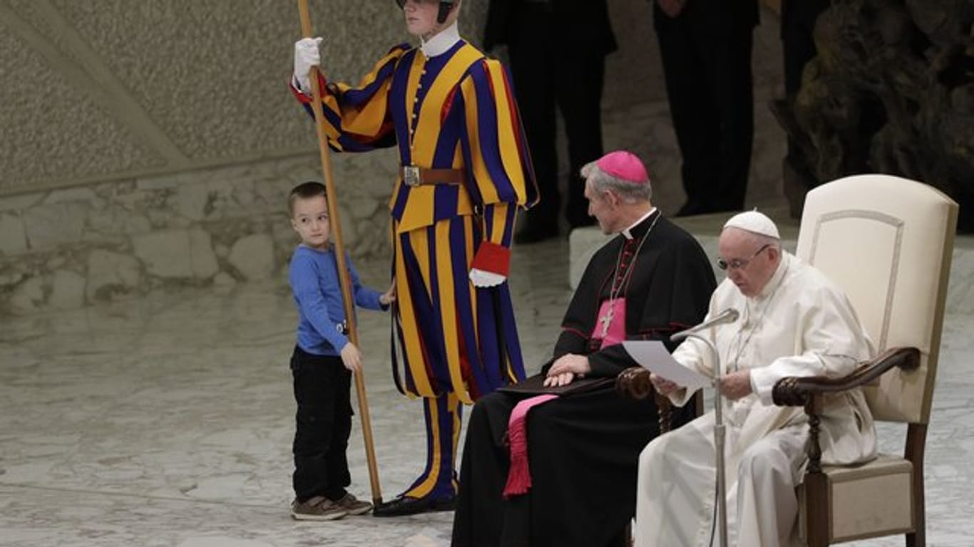Ein Kind möchte mit einem Mitglied der päpstlichen Schweizergarde spielen.