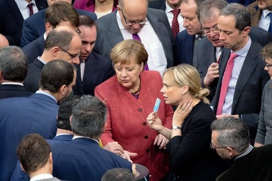 Bundeskanzlerin Angela Merkel (M) gibt bei der namentlichen Abstimmung über den UN-Migrationspakt ihre Stimmkarte ab.