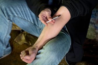 Drogensucht: Ein Mann sitzt unter einer Brücke am Fluss Wishkah und setzt sich mit einer Spritze einen Schuss Heroin.
