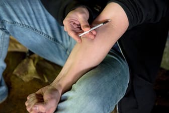 Drogensucht: Ein Mann sitzt unter einer Brücke am Fluss Wishkah und setzt sich mit einer Spritze einen Schuss Heroin.