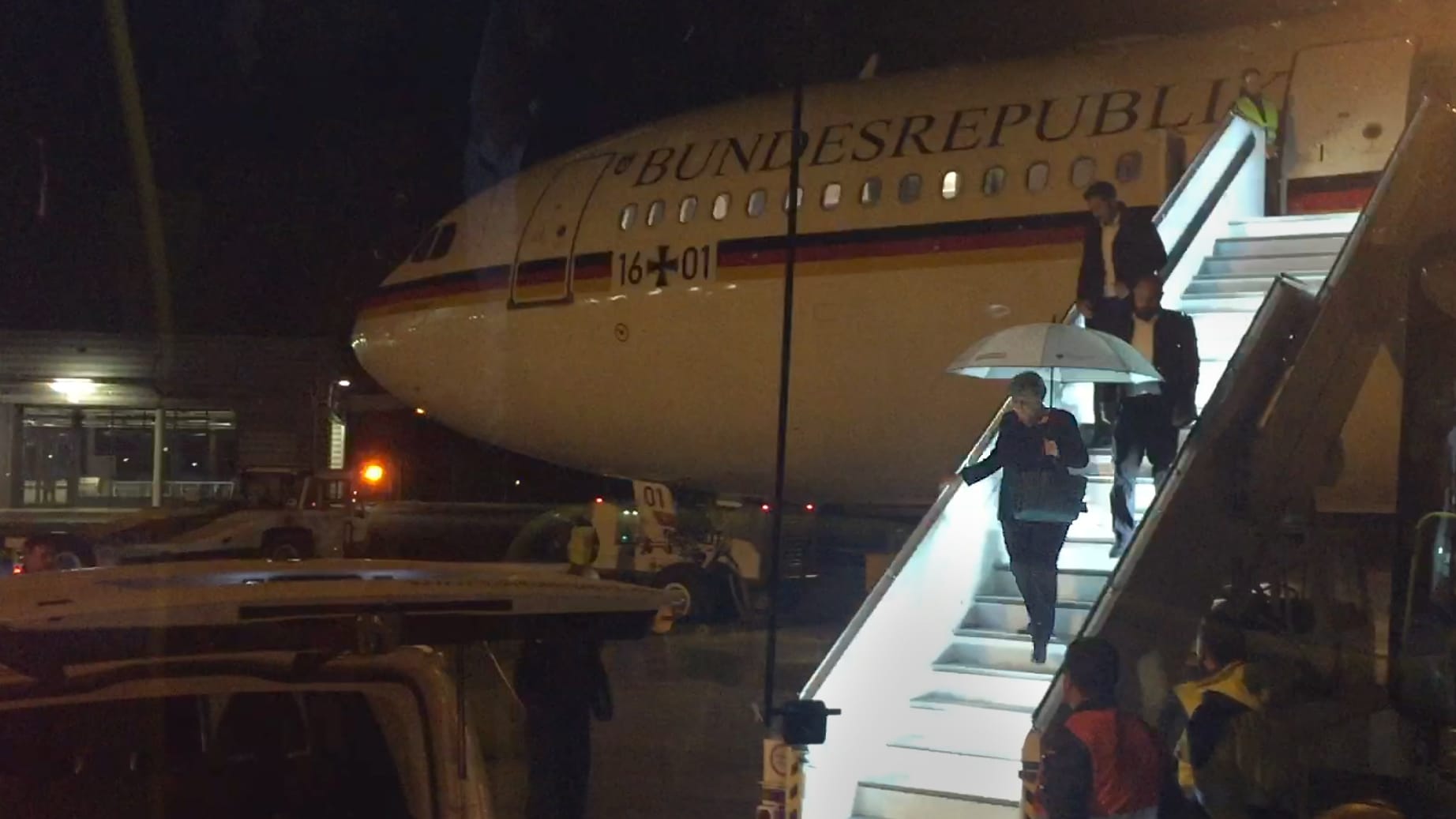 Angela Merkel verlässt mit einem Regenschirm in der Hand auf dem Rollfeld des Flughafens in Köln den Kanzler-Airbus "Konrad Adenauer": Wegen eines technischen Defekts am Flugzeug hat Merkel ihren Flug von Berlin zum G20-Gipfel in Buenos Aires am Donnerstagabend unterbrechen müssen.