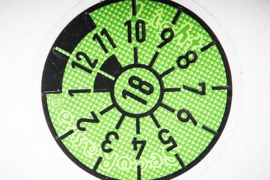 Die schwarze Markierung der HU-Plakette zeigt wie ein Stundenzeiger eines Zifferblatts den fälligen Monat des Prüftermins an - hier auf der "10-Uhr"-Position der Oktober.