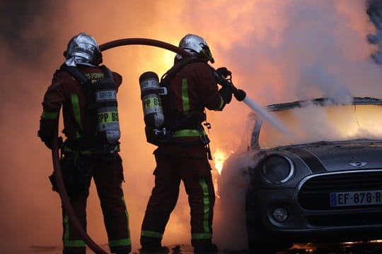 Feuerwehrleute löschen bei einem Protest der "Gelbwesten" in der Nähe der Champs-Elysees ein brennendes Auto.