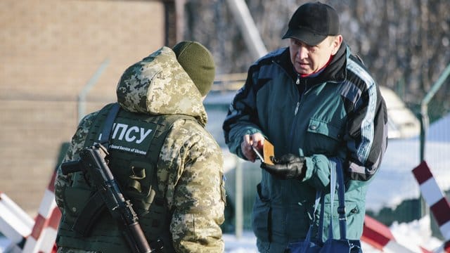 An der ukrainisch-russischen Grenze bei Hoptivka überprüft ein ukrainischer Grenzschutzbeamter die Dokumente eines Mannes. An der ukrainisch-russischen Grenze bei Hoptivka überprüft ein ukrainischer Grenzschutzbeamter die Dokumente eines Mannes.