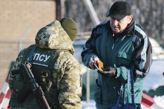 An der ukrainisch-russischen Grenze bei Hoptivka überprüft ein ukrainischer Grenzschutzbeamter die Dokumente eines Mannes.