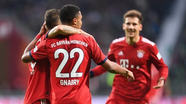 Bayerns Joshua Kimmich (l) umarmt den Torschützen zum 1:0, Serge Gnabry, rechts kommt Leon Goretzka.