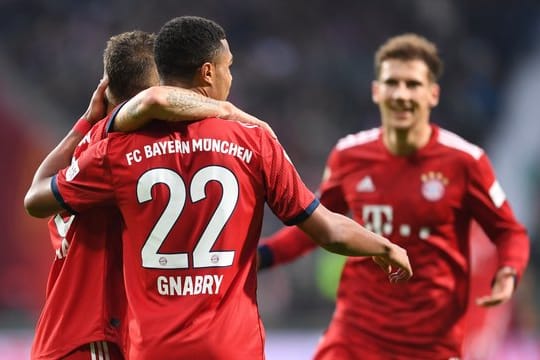 Bayerns Joshua Kimmich (l) umarmt den Torschützen zum 1:0, Serge Gnabry, rechts kommt Leon Goretzka.