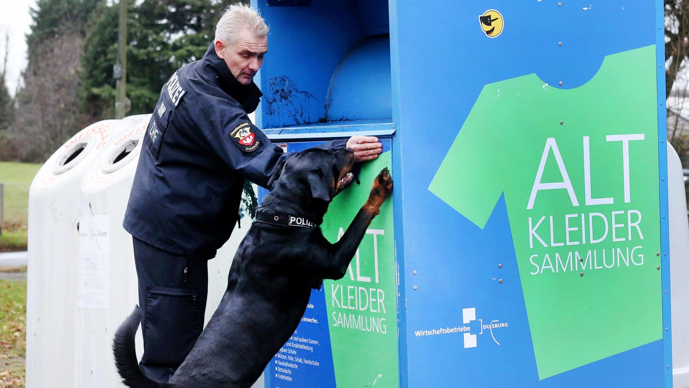 Polizist und Spürhund an einem Duisburger Altkleidercontainer: In einem der etwa 300 Behälter in der Stadt muss "Mia" abgelegt worden sein.