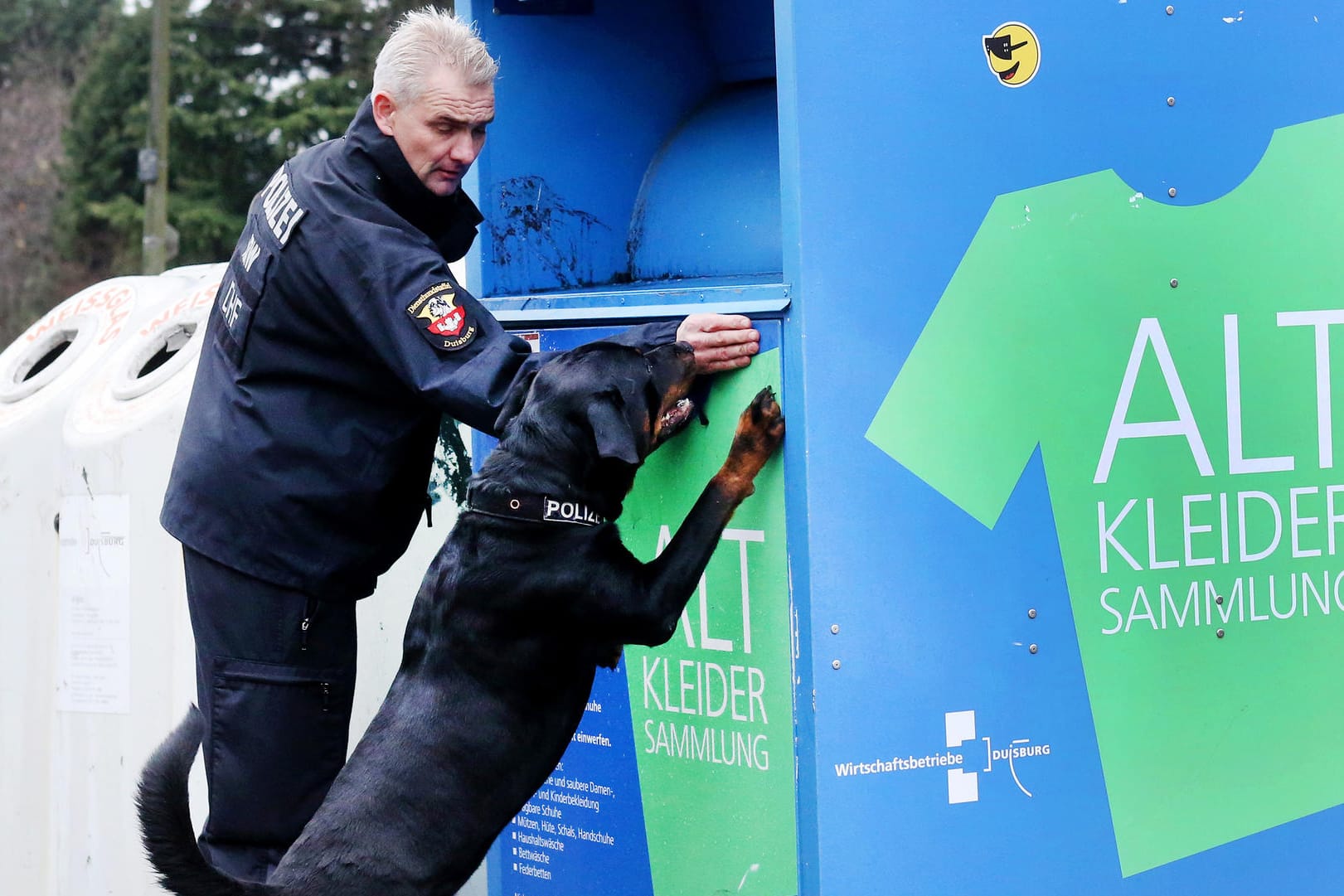 Polizist und Spürhund an einem Duisburger Altkleidercontainer: In einem der etwa 300 Behälter in der Stadt muss "Mia" abgelegt worden sein.