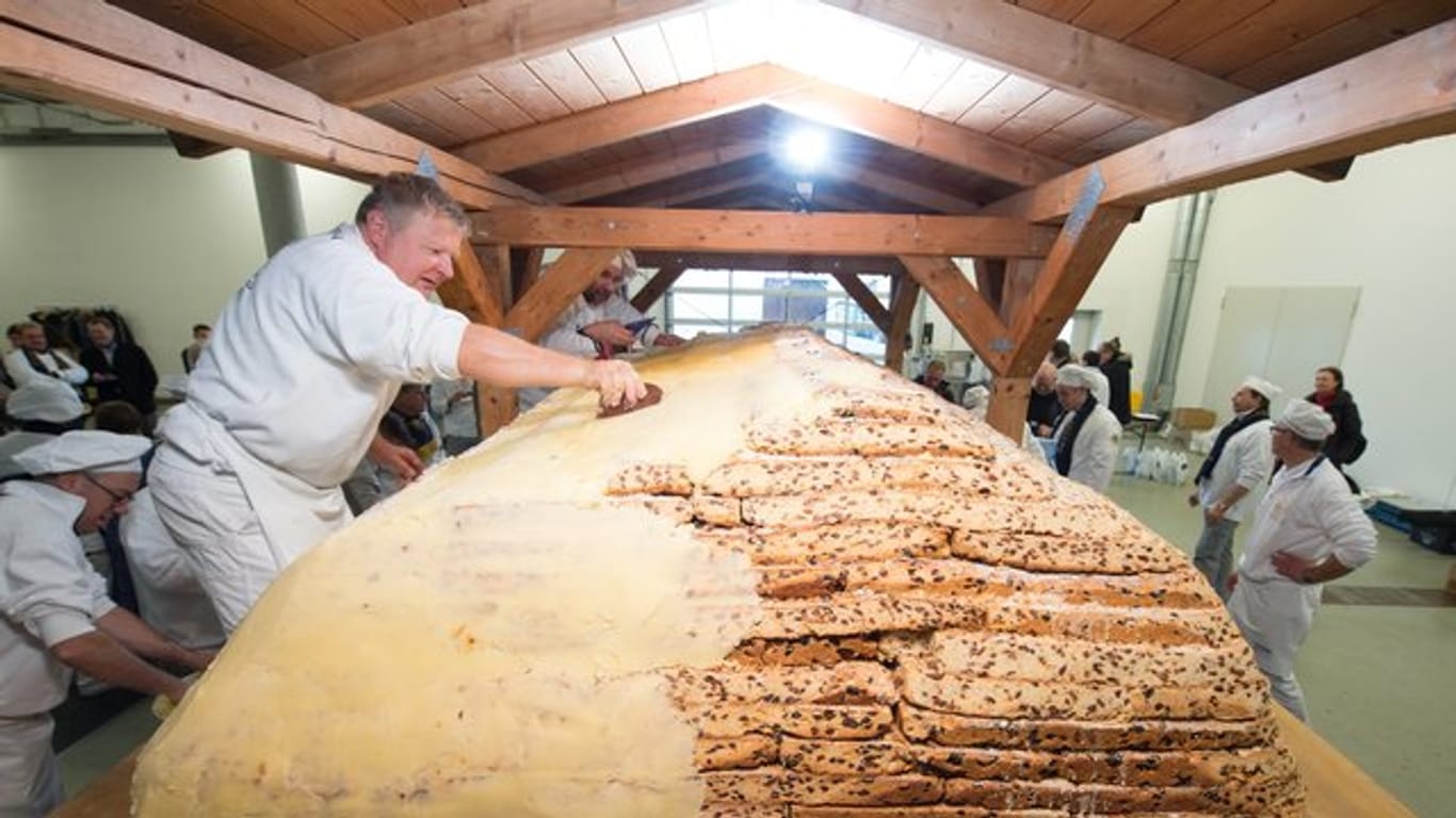Bäckermeister Thomas Schmidt bestreicht den Riesenstollen mit Butter und Zucker.