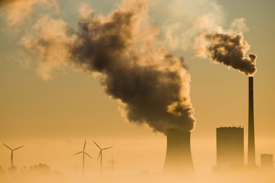 Vergangenheit und Zukunft: Windräder drehen sich hinter einem Kohlekraftwerk.