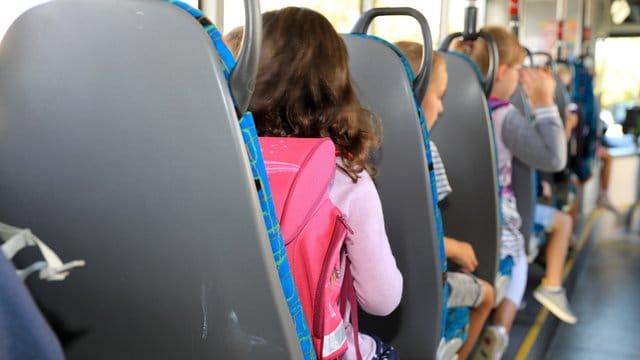 Kinder sitzen mit ihrem Ranzen in einem Schulbus (Symbolbild): Die Polizei ermittelt gegen einen Busfahrer.